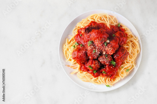 Homemade spaghetti and meatballs with tomato sauce. Top view on a white marble background.