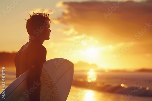 Surfer silhouetted against a golden sunset, readying for the waves. © Larisa