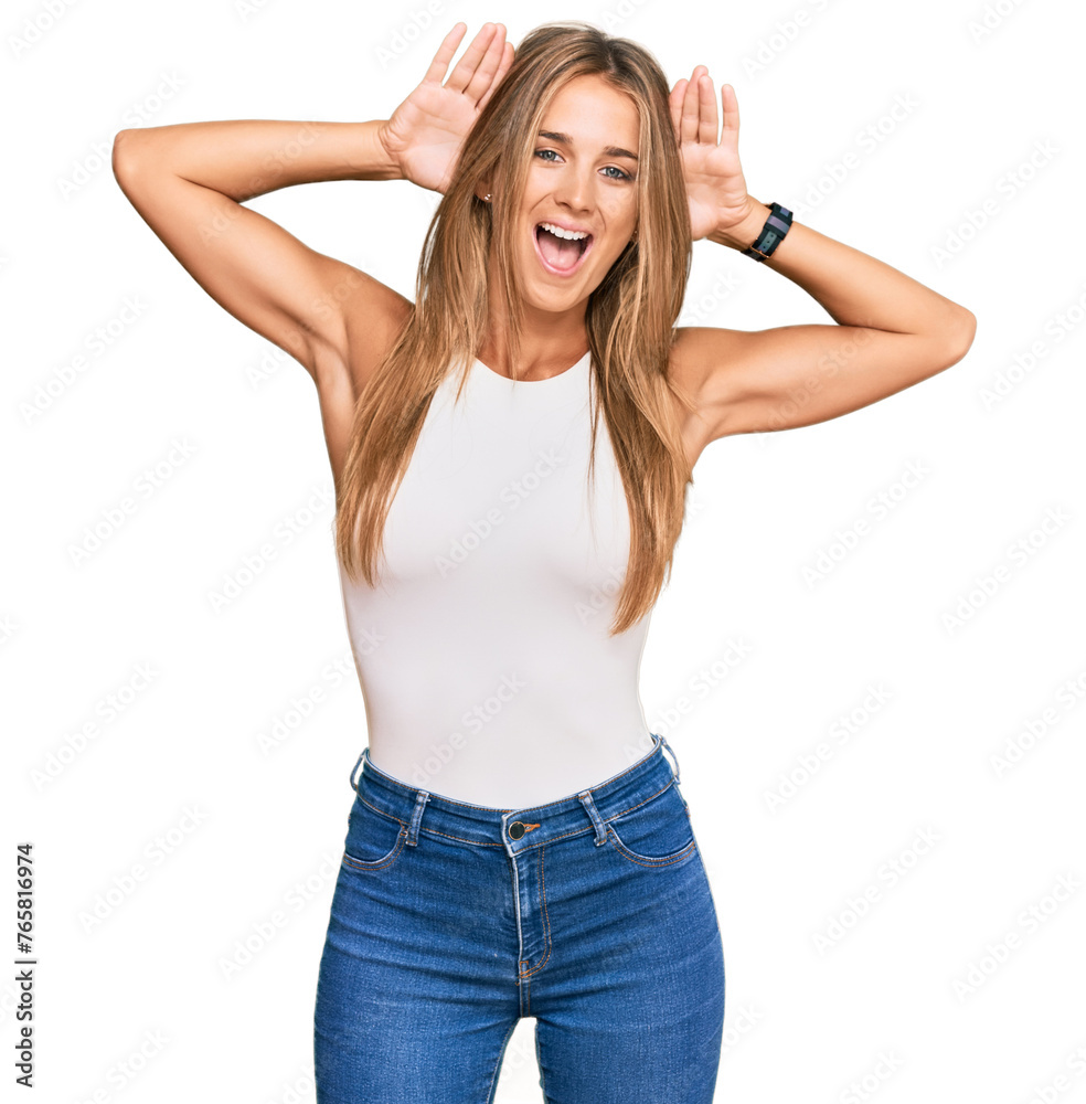 Young blonde woman wearing casual style with sleeveless shirt smiling cheerful playing peek a boo with hands showing face. surprised and exited