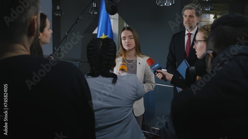 Positive European female politician answers journalists questions, gives interview for media and television in European Parliament building. Representative of the European Union at press conference. photo