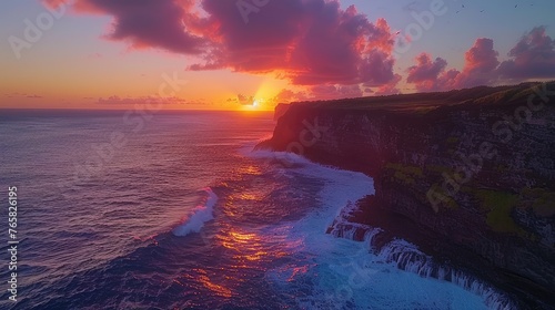 Vibrant sunset over ocean cliffs with waves crashing against the rocky shoreline and birds in the sky.