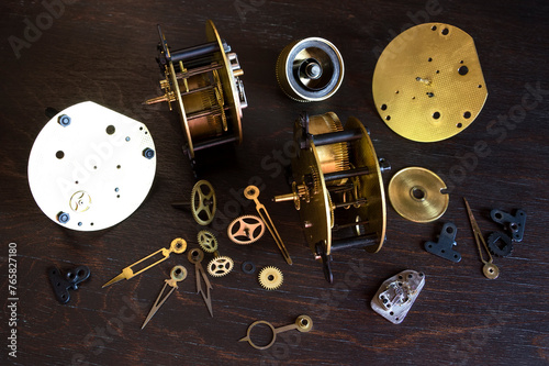 Old clockwork movements and parts are spread out on a table.