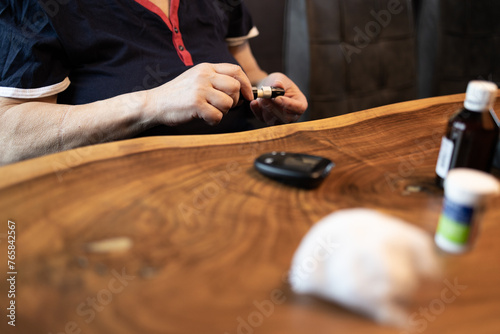 Senior woman measuring blood sugar with glucometer in kitchen