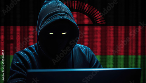 Hacker in a dark hoodie sitting in front of a monitors with Malawi flag and background cyber security concept