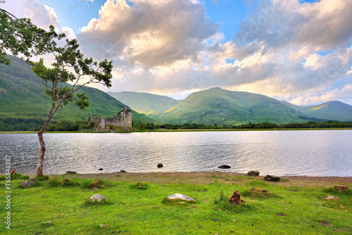 View of Kilchurn Castle on Lock Awe in the highlands of Scotland with lone tree near sunset