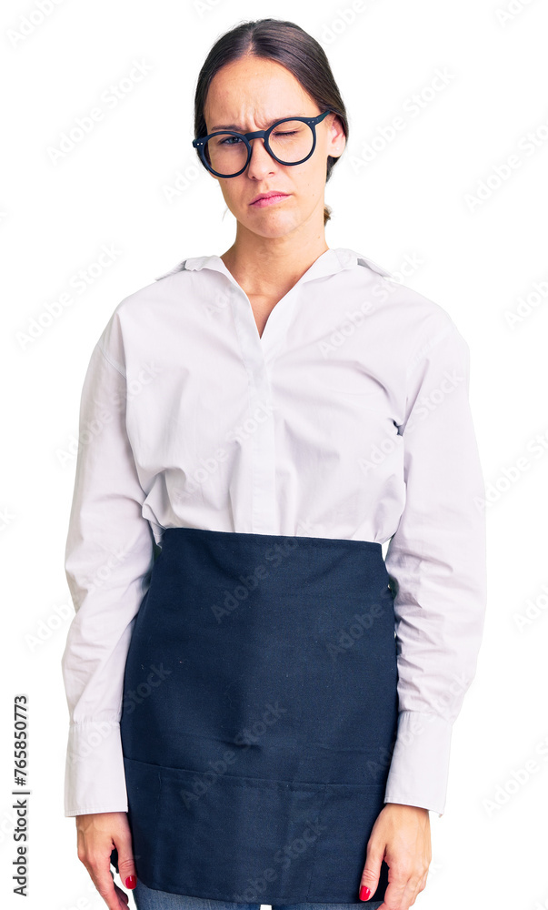 Beautiful brunette young woman wearing professional waitress apron skeptic and nervous, frowning upset because of problem. negative person. Beautiful brunette young woman wearing professional waitress apron skeptic and nervous, frowning upset because of problem. negative person.