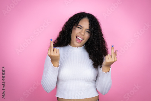 African american woman wearing casual sweater over pink background showing middle finger doing fuck you bad expression, provocation and rude attitude. screaming excited photo