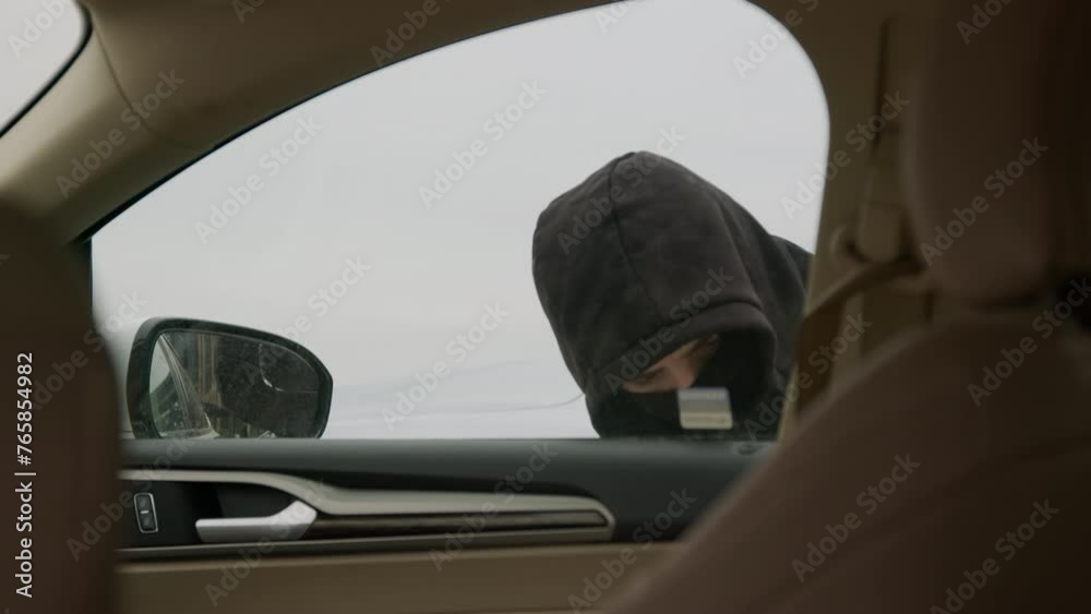 Car thief burglar unlocks vehicle view from inside car. Car thief burglar actions as he breaks in. Inside car hooded vehicle thief burglar is seen tampering with vehicle security system. Car thief burglar unlocks vehicle view from inside car. Car thief burglar actions as he breaks in. Inside car hooded vehicle thief burglar is seen tampering with vehicle security system.