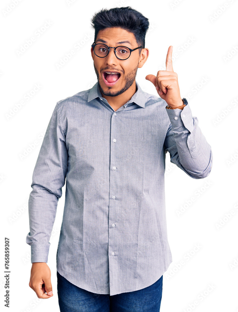 Handsome latin american young man wearing business clothes and glasses pointing finger up with successful idea. exited and happy. number one.