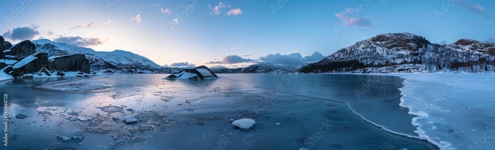 A frozen lake sits nestled among snow-covered mountains, creating a tranquil winter scene