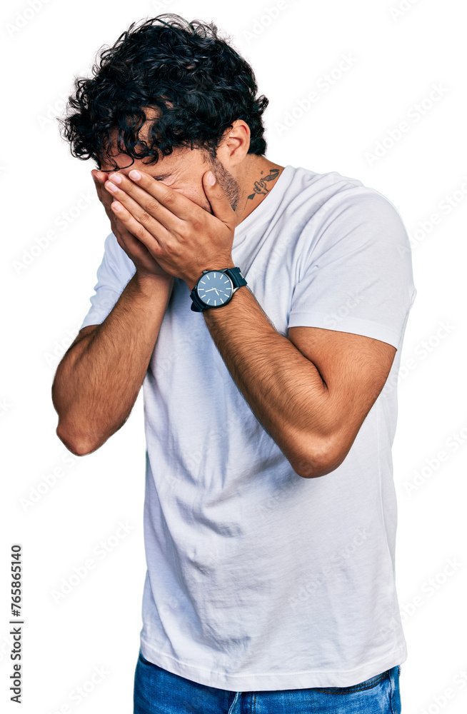 Hispanic young man with beard wearing casual white t shirt with sad expression covering face with hands while crying. depression concept. Hispanic young man with beard wearing casual white t shirt with sad expression covering face with hands while crying. depression concept.