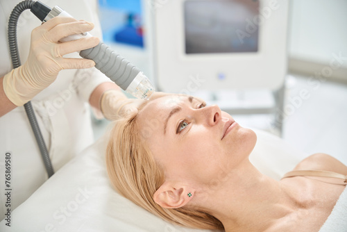 Cosmetologist making microneedle RF-lifting procedure for woman