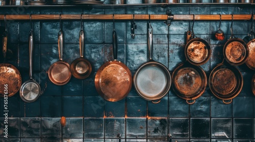  a bunch of pots and pans hanging up on a wall in a room with a blue tiled wall behind them.
