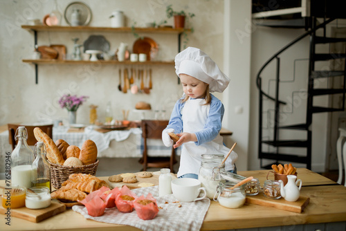 Girl cook 3 years old in a beautiful kitchen, in a chef's hat, in an apron, daylight