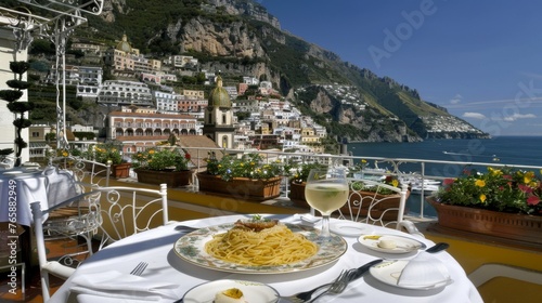  a table with a plate of food and a glass of wine on a balcony overlooking a city and the ocean.