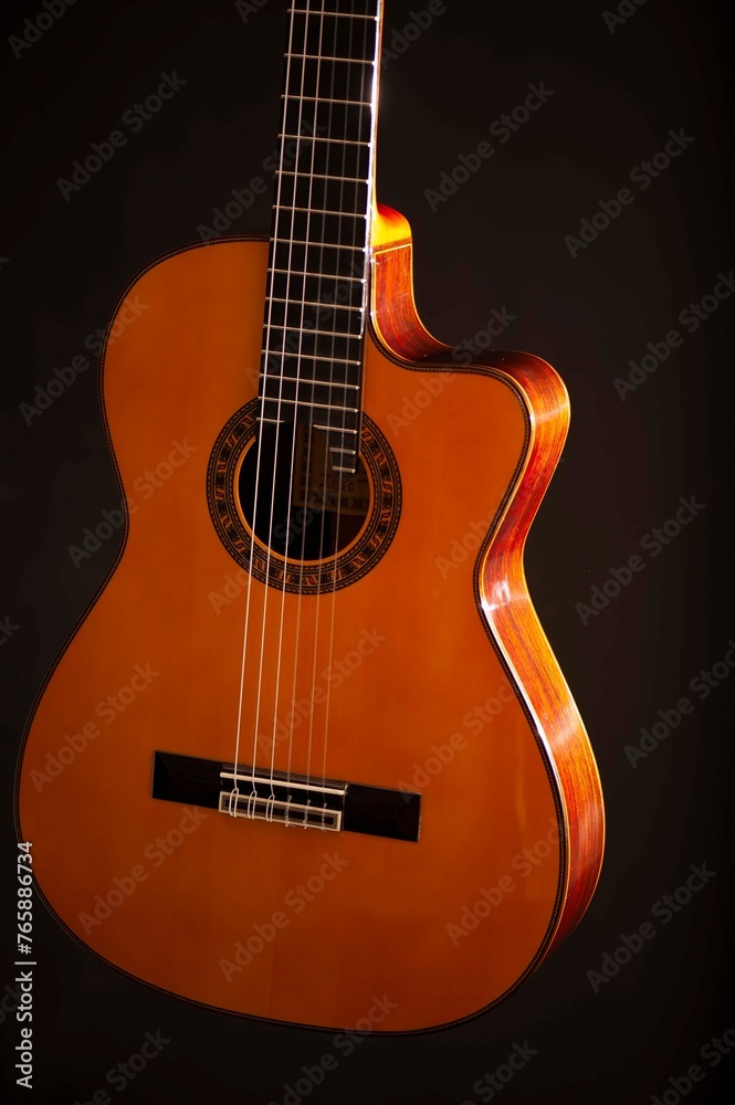 Obraz premium Classical Spanish flamenco guitar close up, dramatically lit isolated on black background with copy space.