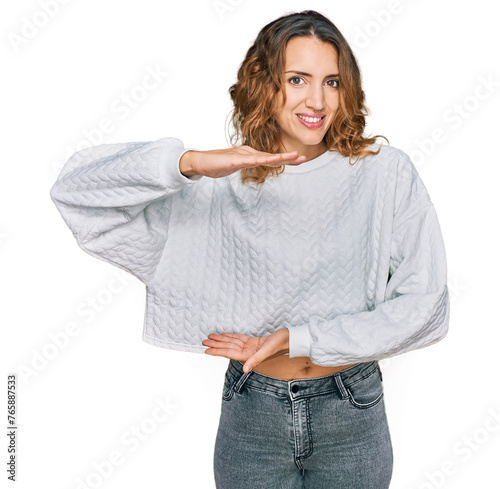 Beautiful young caucasian woman wearing casual winter sweater gesturing with hands showing big and large size sign, measure symbol. smiling looking at the camera. measuring concept.