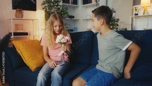 Shy pre-teen boy presenting flowers to a smiling girl, birthday greetings photo