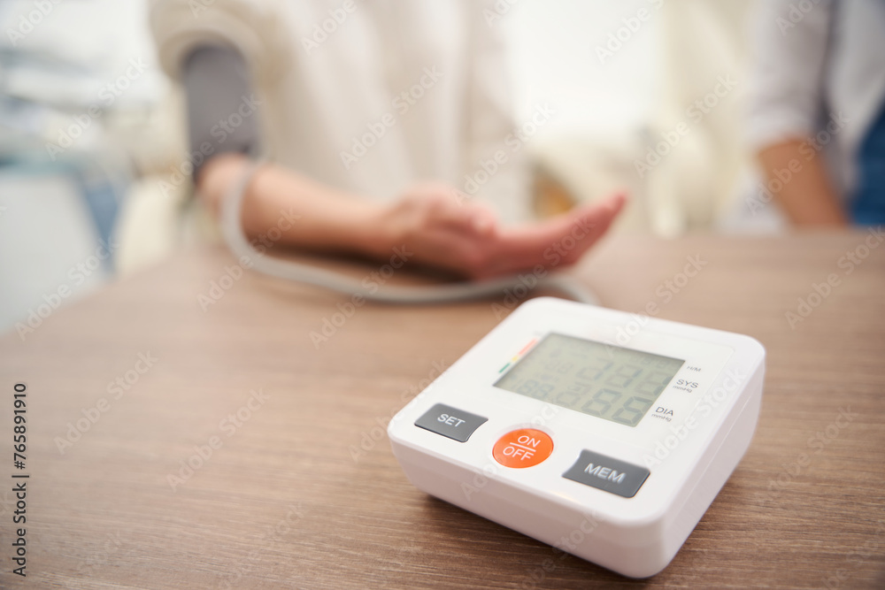 Tonometer on table while blurred patient measuring her pressure with doctor Tonometer on table while blurred patient measuring her pressure with doctor