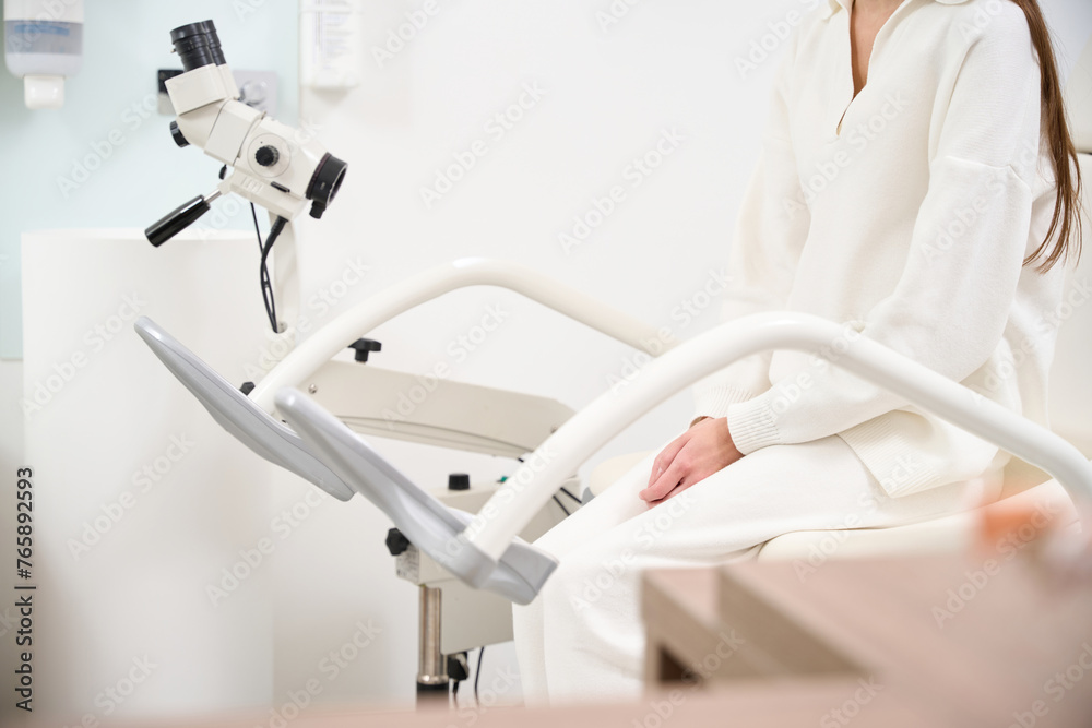 Cropped of female patient sitting and waiting on medical couch in blurred clinic Cropped of female patient sitting and waiting on medical couch in blurred clinic