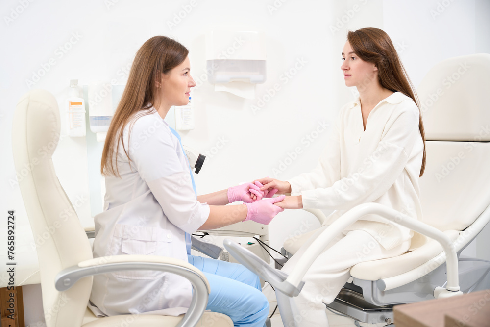 Side of gynecologist and woman patient holding hands and looking at each other Side of gynecologist and woman patient holding hands and looking at each other