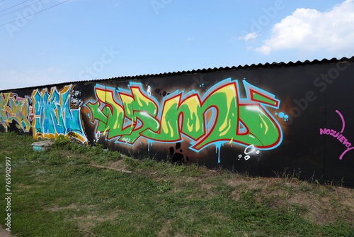 The old wall decorated with paint stains in the style of street art culture. Colorful background of full graffiti painting artwork with bright aerosol outlines on wall. Colored background texture