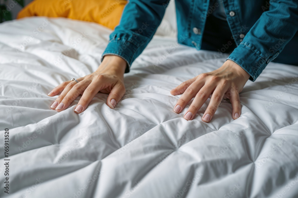 Women's hands on a white mattress on the bed.