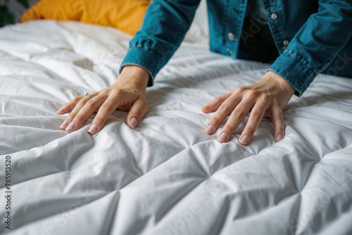 Women s hands on a white mattress on the bed.