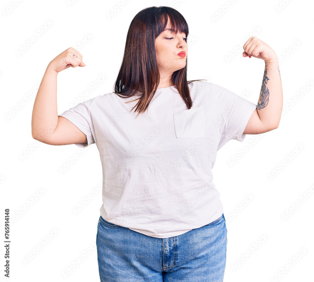 Young plus size woman wearing casual clothes showing arms muscles smiling proud. fitness concept. Young plus size woman wearing casual clothes showing arms muscles smiling proud. fitness concept.