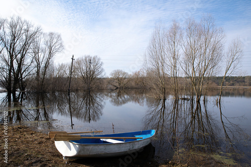 Fototapeta Naklejka Na Ścianę i Meble -  An empty boat on the shore of the overflowing floodplain of the river in spring.