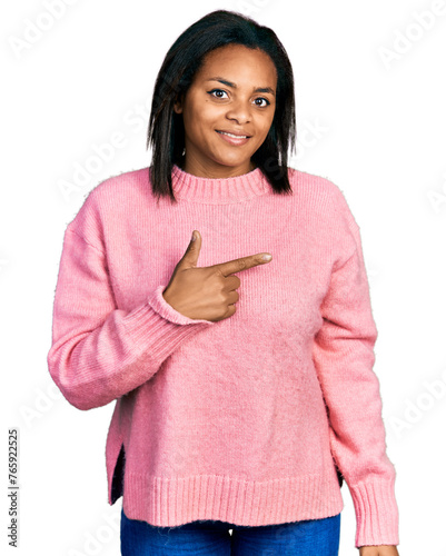 Beautiful hispanic woman wearing casual winter sweater cheerful with a smile on face pointing with hand and finger up to the side with happy and natural expression