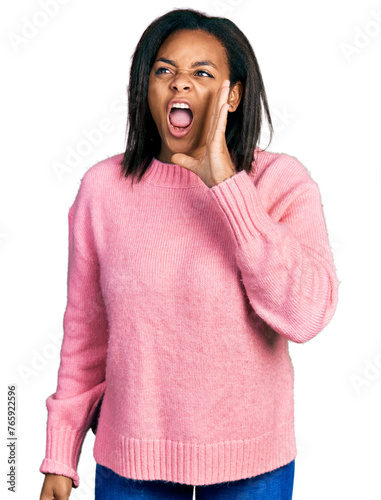 Beautiful hispanic woman wearing casual winter sweater shouting and screaming loud to side with hand on mouth. communication concept.