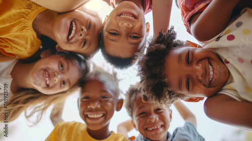 A vibrant group of children from diverse backgrounds gathered in a sunlit health center lobby, huddled together in a circle, their laughter and joy captured as they look down at th