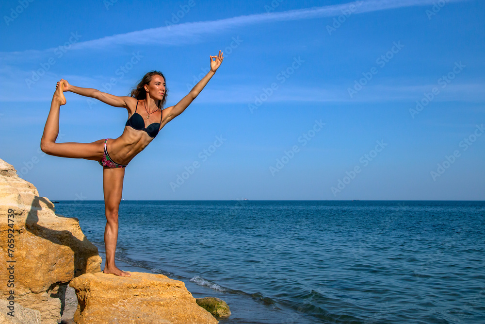 Beautiful girl - yoga in Natarajasana pose against the blue sky Beautiful girl - yoga in Natarajasana pose against the blue sky