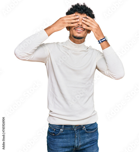 Young arab man wearing casual winter sweater covering eyes with hands smiling cheerful and funny. blind concept.