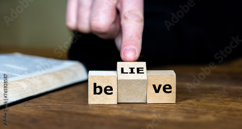 Wooden cubes form the words believe and lie. Symbol for criticizing religions. photo