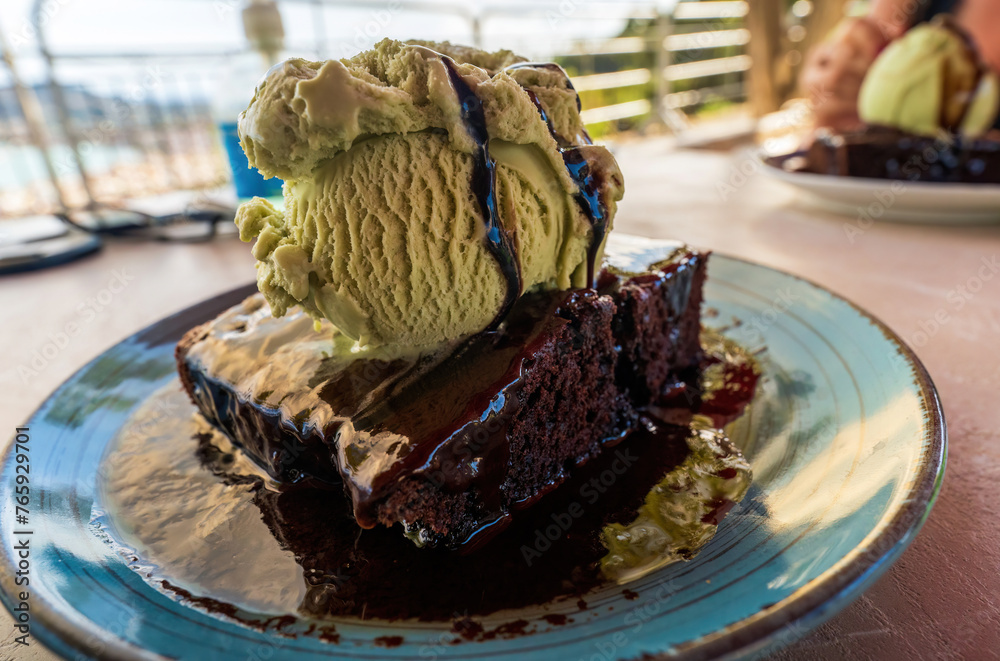 Warm Chocolate brownie cake with hot fudge sauce and vanilla ice cream on top on a plate served in a restaurant