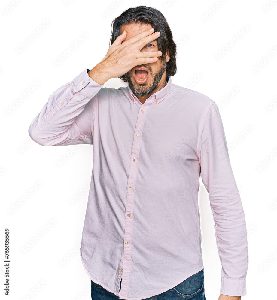 Middle age handsome man wearing business shirt peeking in shock covering face and eyes with hand, looking through fingers with embarrassed expression. Middle age handsome man wearing business shirt peeking in shock covering face and eyes with hand, looking through fingers with embarrassed expression.