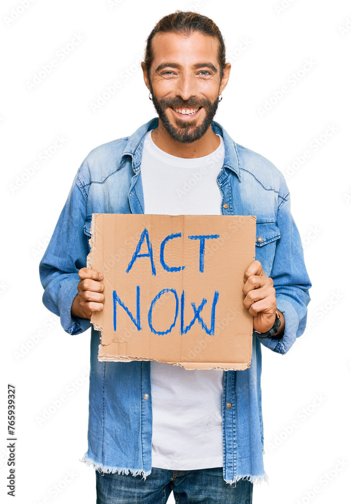 Attractive man with long hair and beard holding act now banner looking positive and happy standing and smiling with a confident smile showing teeth Attractive man with long hair and beard holding act now banner looking positive and happy standing and smiling with a confident smile showing teeth