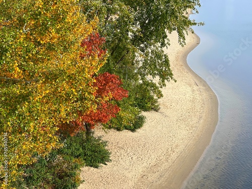 Autumn trees with red yellow foliage on the river bank.