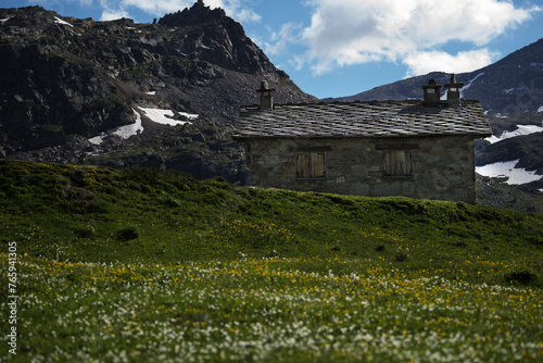 Mountain landscape with mountains in the background and view of rock stone hut, used as a cheese factory, in the Gran Paradiso National Park, Aosta Valley, Italy