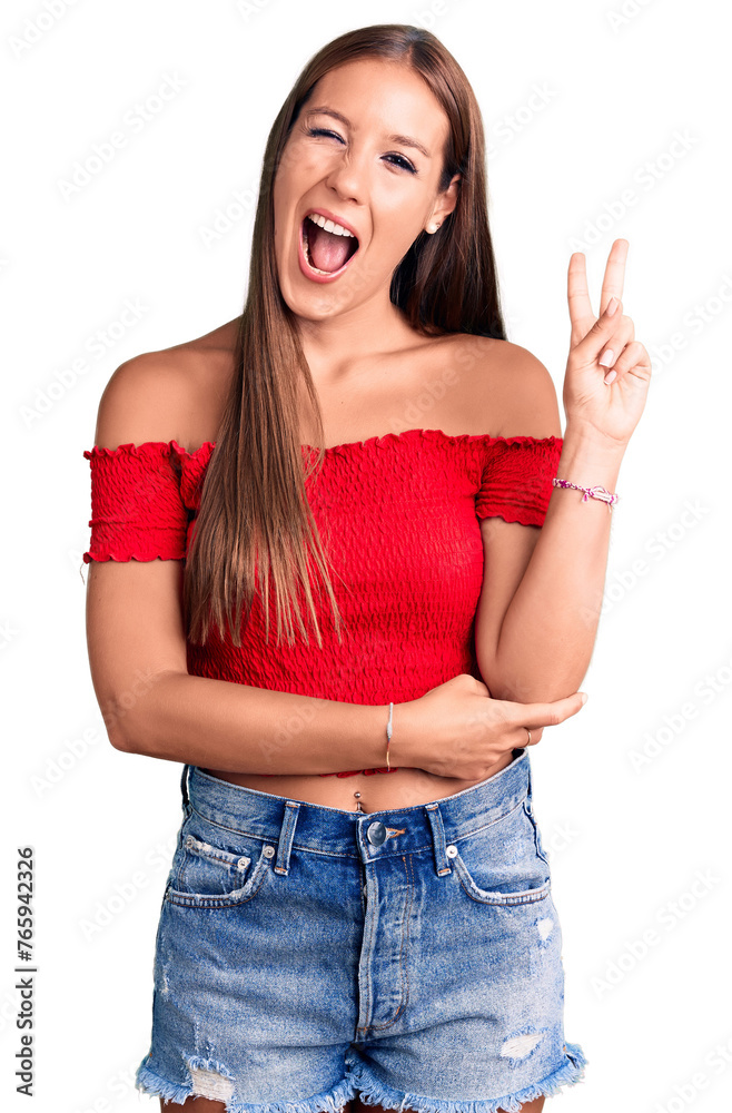 Young beautiful hispanic woman wearing casual clothes smiling with happy face winking at the camera doing victory sign. number two. Young beautiful hispanic woman wearing casual clothes smiling with happy face winking at the camera doing victory sign. number two.