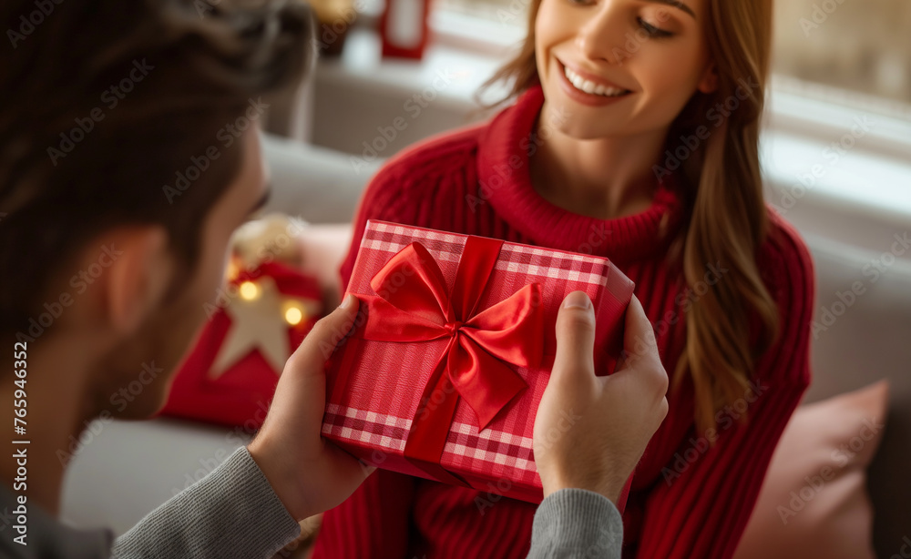 A man presenting a red gift box to a smiling woman, both seated in a festive environment, highlighting the joy of giving. A man presenting a red gift box to a smiling woman, both seated in a festive environment, highlighting the joy of giving.