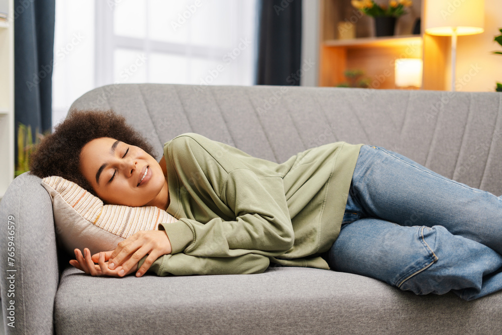 Beautiful, African American woman with curly hair lying down, sleeping on pillow