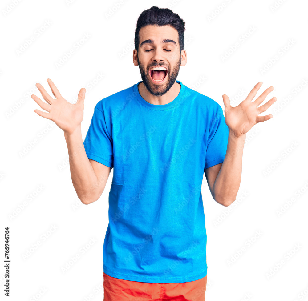 Young handsome man with beard wearing casual t-shirt celebrating mad and crazy for success with arms raised and closed eyes screaming excited. winner concept Young handsome man with beard wearing casual t-shirt celebrating mad and crazy for success with arms raised and closed eyes screaming excited. winner concept