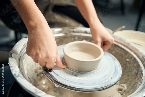 Unrecognizable woman making ceramics products on pottery wheel