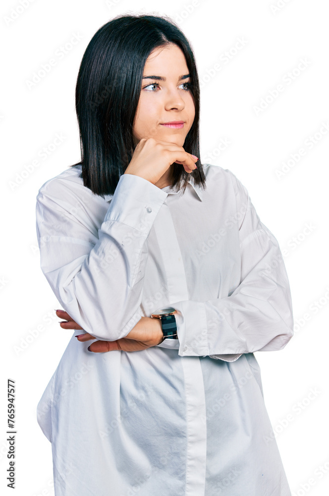 Young brunette woman with blue eyes wearing oversize white shirt with hand on chin thinking about question, pensive expression. smiling and thoughtful face. doubt concept. Young brunette woman with blue eyes wearing oversize white shirt with hand on chin thinking about question, pensive expression. smiling and thoughtful face. doubt concept.