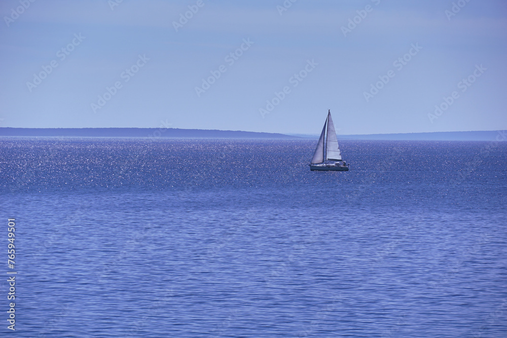 The sailboat sails calmly on the blue sea in the calm of the day