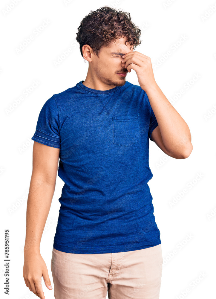 Young handsome man with curly hair wearing casual clothes tired rubbing nose and eyes feeling fatigue and headache. stress and frustration concept. Young handsome man with curly hair wearing casual clothes tired rubbing nose and eyes feeling fatigue and headache. stress and frustration concept.
