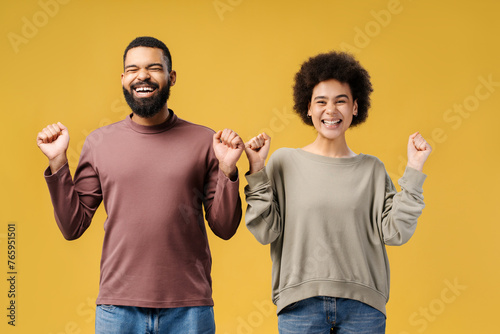 Smiling, attractive African American couple winners, gesturing with closed eyes rejoicing, win money